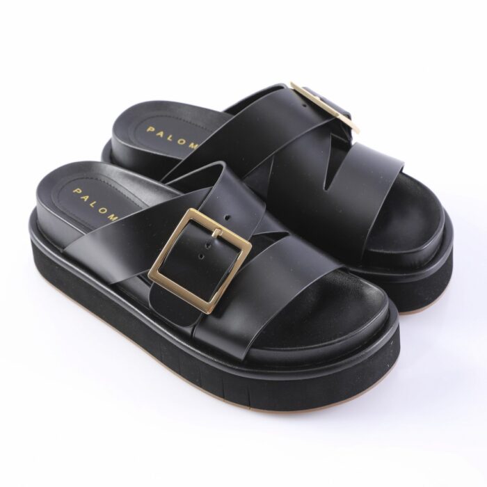 Black platform sandals with two wide crisscross straps and a gold square buckle on the front strap, on a white background
