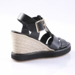 Black leather wedge sandal with braided jute heel, gold buckle, and rubber sole in side view.