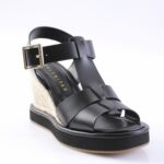 Black wedge sandal with leather straps and beige jute-covered heel, on a light background.