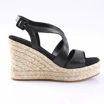 Black leather wedge sandal with braided jute platform and ankle strap with buckle, side view.