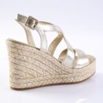 Gold metallic wedge sandal with braided jute platform and ankle strap on a light background