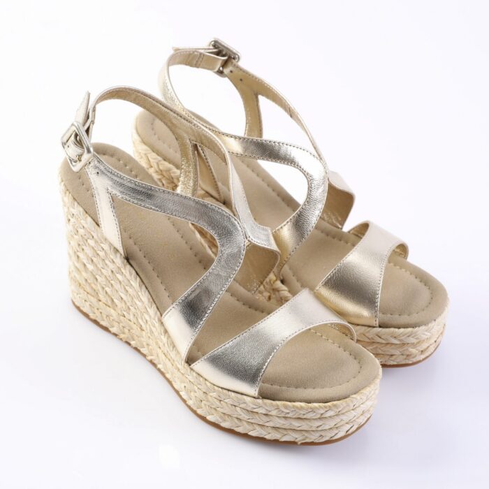 Gold metallic wedge sandals with a braided espadrille platform and multiple straps on a white background.