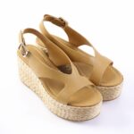 Tan leather wedge sandals with a braided jute platform and ankle strap, photographed on a white background.