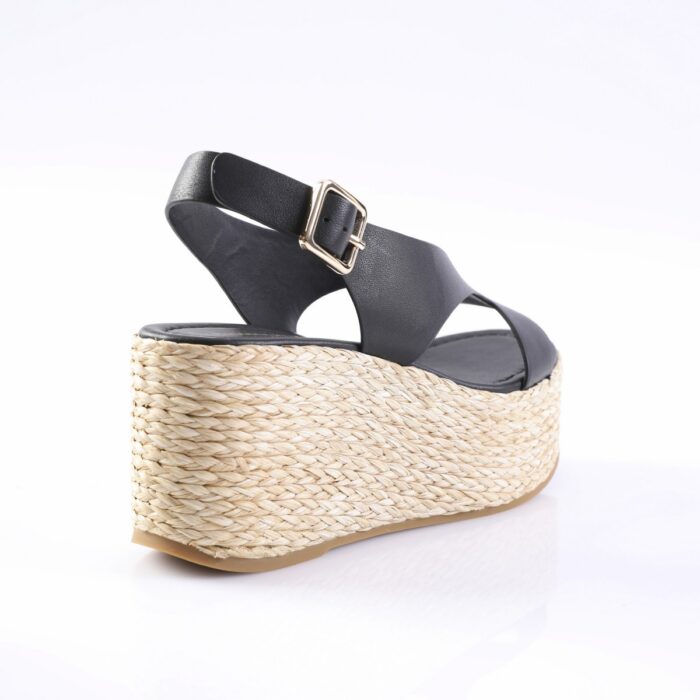 Black leather platform sandal with a braided jute wedge and gold buckle at the ankle strap