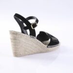 Black wedge espadrille sandal with an ankle strap and gold buckle, rope-wrapped sole visible from the side.