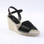 Black suede wedge sandal with an ankle strap and braided jute sole, front view shows stitching detail.