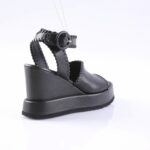 Black platform sandal with stitched straps and back loop on a white studio backdrop, angled to show heel and sole detail.