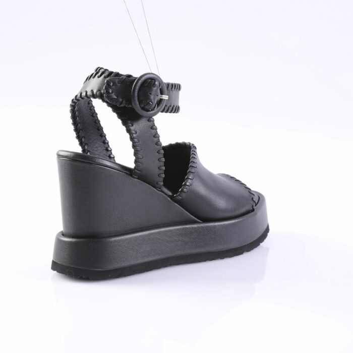 Black platform sandal with stitched straps and back loop on a white studio backdrop, angled to show heel and sole detail.