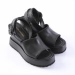 Black platform sandals with thick soles and hand-stitched edges; open toe and ankle strap visible on white background.