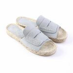 Light blue suede slide espadrille sandals with a woven rope sole on a white background.