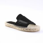 Black suede slide sandal with a rope-wrapped espadrille sole and white stitching detail at the strap.