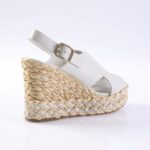 White leather wedge sandal with a braided jute platform and ankle strap with a gold buckle