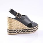 Black leather wedge sandal with an ankle strap and gold buckle, set on a woven braided-strap espadrille platform
