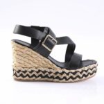 Black strappy wedge sandal with a braided jute platform and gold buckle.