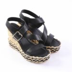 Black leather wedge sandals with ankle strap and buckle, featuring a braided jute sole.