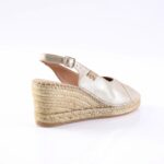 Metallic champagne espadrille wedge sandal with ankle strap and braided jute sole on a white background.