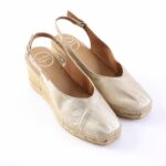Beige metallic wedge espadrille sandals with ankle straps on a white background
