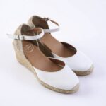 White espadrille wedge sandals with ankle straps and woven jute sole on a white background, front view.
