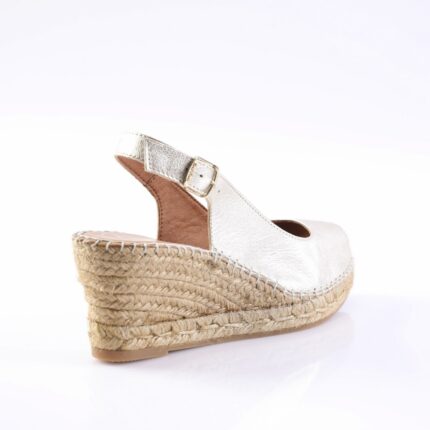 Silver wedge espadrille sandal with ankle strap and buckle on a braided jute sole, side view of the shoe.
