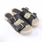 Black double-strap sandals with metal buckles and cushioned cork footbed, viewed from above.