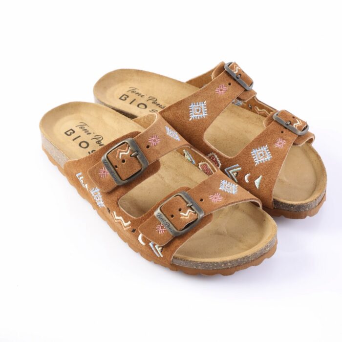 Brown suede sandals with two buckle straps and colorful embroidered geometric patterns; cork footbed and ridged sole.