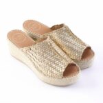 Gold woven espadrille wedge sandals with open toes and thick rope sole on a white background