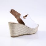 White espadrille wedge sandal with a brown leather ankle strap and braided jute platform.
