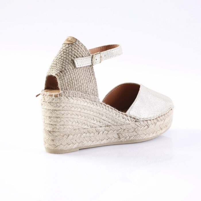 Beige espadrille wedge sandal with a braided rope sole and ankle strap.