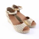 Gold woven espadrille sandals with ankle straps on a white background.